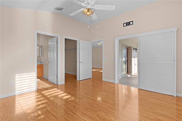 unfurnished bedroom featuring light hardwood / wood-style flooring, a walk in closet, a closet, and ceiling fan