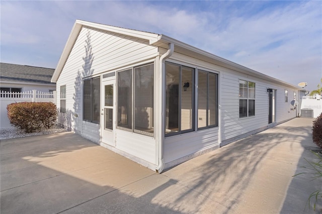 view of side of property with central AC, a sunroom, and a patio