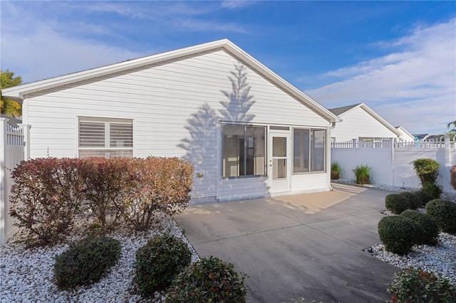 rear view of house featuring a sunroom and a patio area