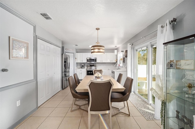 tiled dining room featuring sink and a textured ceiling