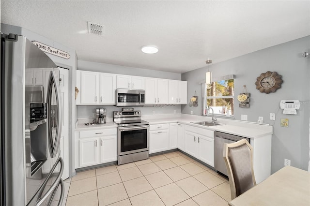 kitchen featuring light tile patterned flooring, appliances with stainless steel finishes, pendant lighting, sink, and white cabinets