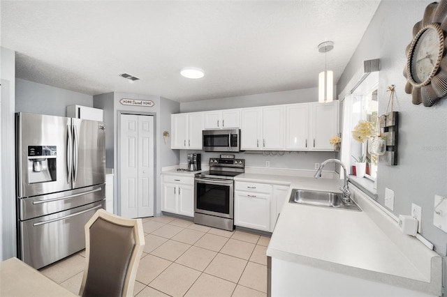 kitchen featuring light tile patterned flooring, appliances with stainless steel finishes, pendant lighting, white cabinetry, and sink