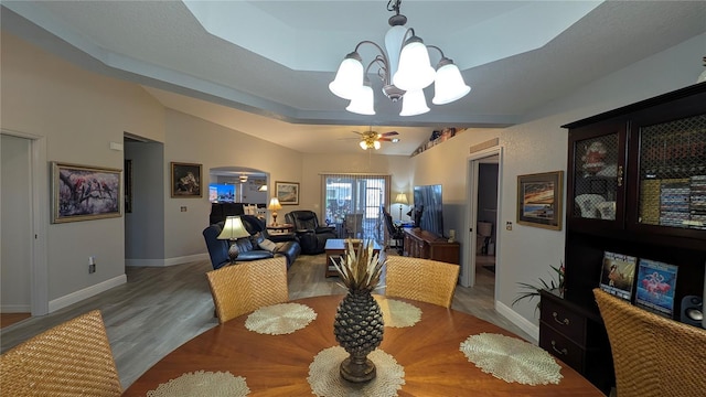 dining area featuring wood-type flooring and ceiling fan with notable chandelier