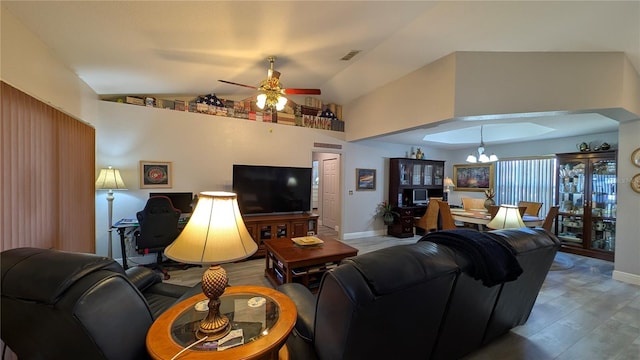 living room with ceiling fan with notable chandelier, wood-type flooring, and vaulted ceiling