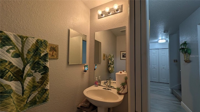 bathroom featuring sink, wood-type flooring, and a textured ceiling