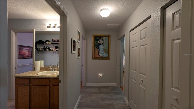 hallway with sink, a textured ceiling, and dark hardwood / wood-style floors