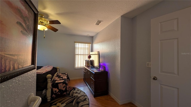 bedroom featuring ceiling fan, hardwood / wood-style floors, and a textured ceiling