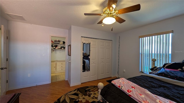 bedroom with hardwood / wood-style floors, a textured ceiling, ceiling fan, and a closet