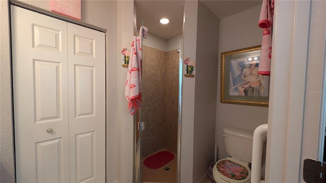 bathroom featuring toilet and a tile shower