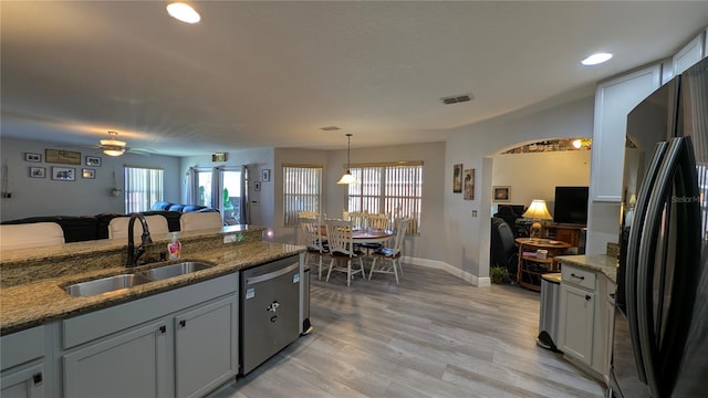 kitchen with pendant lighting, sink, stone countertops, stainless steel dishwasher, and black fridge