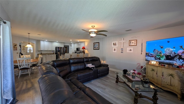 living room with ceiling fan, hardwood / wood-style floors, and a textured ceiling