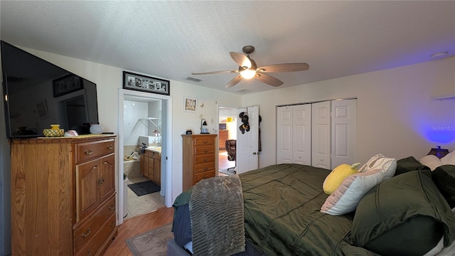 bedroom featuring ceiling fan, connected bathroom, a textured ceiling, a closet, and light wood-type flooring