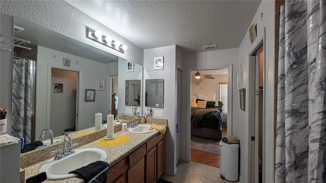 bathroom featuring ceiling fan, tile patterned flooring, vanity, a textured ceiling, and walk in shower