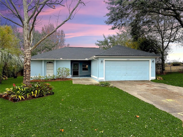 single story home featuring a garage and a yard