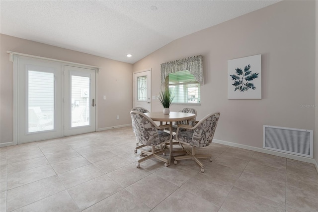 tiled dining area with vaulted ceiling and a textured ceiling