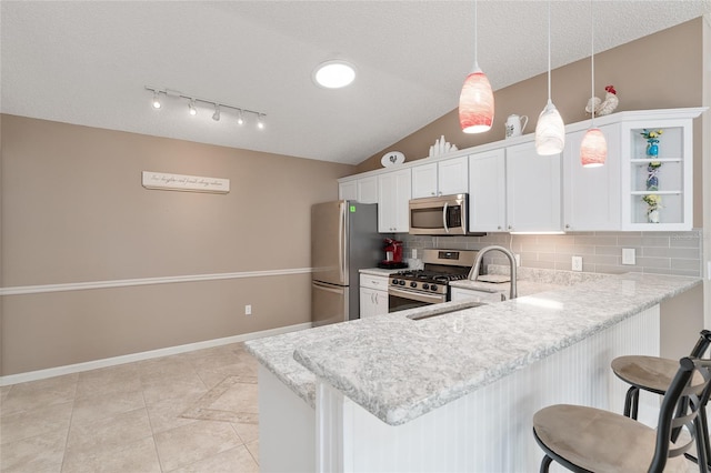 kitchen with white cabinetry, a kitchen breakfast bar, pendant lighting, stainless steel appliances, and decorative backsplash