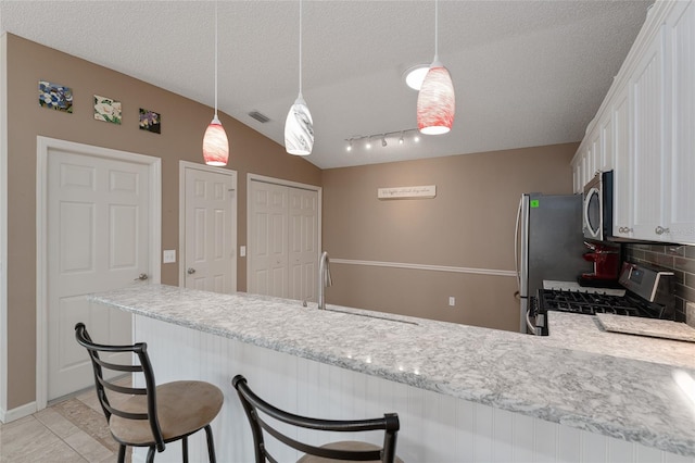 kitchen with white cabinetry, stainless steel appliances, kitchen peninsula, and a textured ceiling