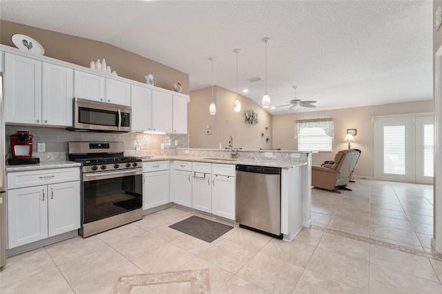 kitchen featuring vaulted ceiling, white cabinetry, appliances with stainless steel finishes, and hanging light fixtures