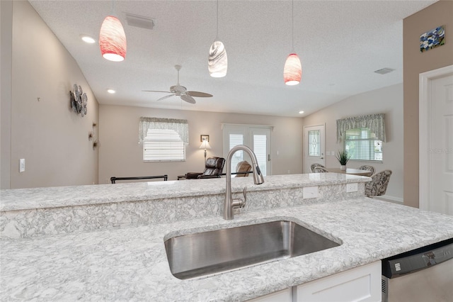 kitchen with lofted ceiling, sink, white cabinetry, dishwasher, and pendant lighting