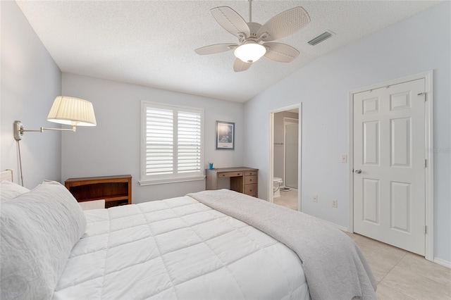 bedroom featuring light tile patterned floors, ensuite bath, ceiling fan, a textured ceiling, and vaulted ceiling