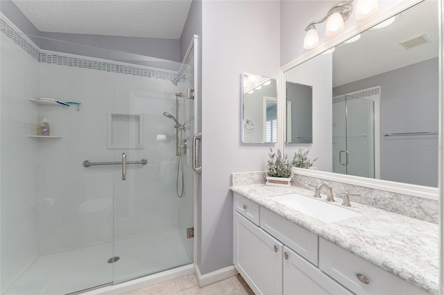 bathroom with tile patterned floors, a shower with shower door, a textured ceiling, and vanity