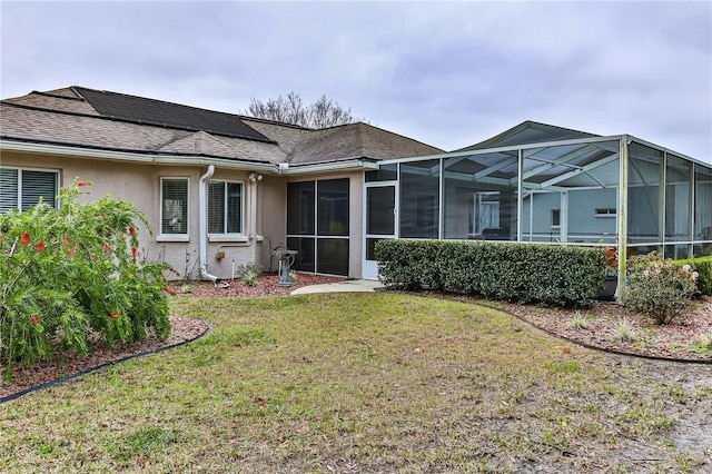 rear view of house with glass enclosure and a lawn