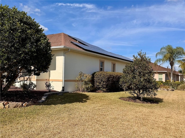 view of side of home with a yard and solar panels