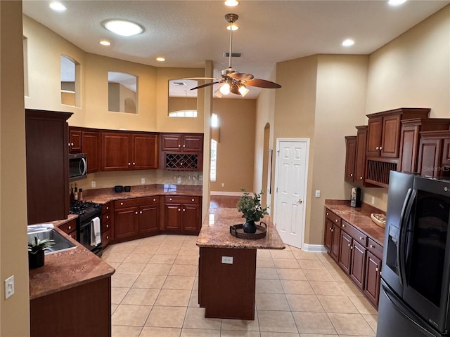 kitchen featuring appliances with stainless steel finishes, sink, a kitchen island, and a high ceiling