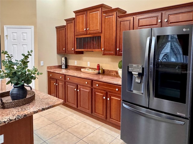 kitchen with light stone countertops, light tile patterned floors, and stainless steel fridge