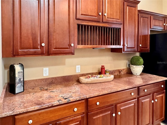 kitchen with light stone counters and black fridge