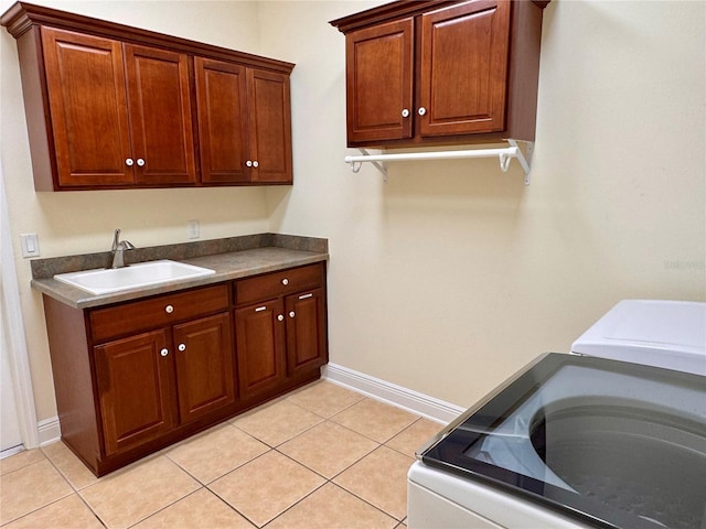 laundry area featuring sink, light tile patterned floors, washer / clothes dryer, and cabinets