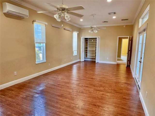 spare room featuring hardwood / wood-style flooring, ceiling fan, ornamental molding, and a wall unit AC