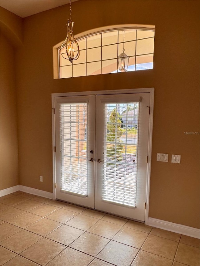 doorway with baseboards, light tile patterned floors, an inviting chandelier, and french doors