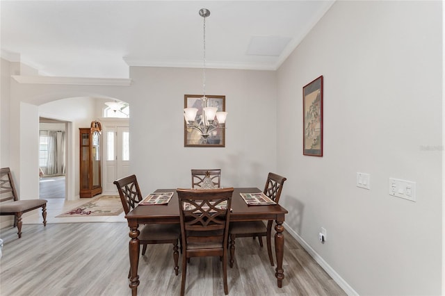 dining area with hardwood / wood-style flooring, crown molding, and a notable chandelier