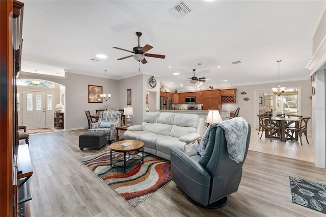 living room with crown molding, ceiling fan with notable chandelier, and light hardwood / wood-style floors