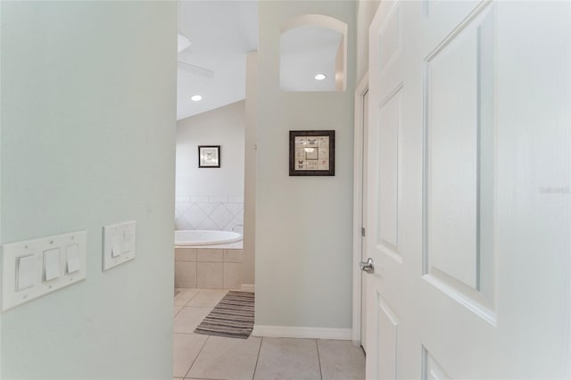 bathroom with vaulted ceiling, tiled bath, and tile patterned flooring