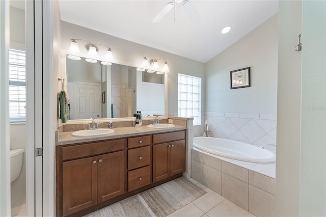 bathroom featuring vaulted ceiling, tile patterned flooring, vanity, ceiling fan, and tiled tub