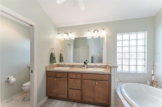 bathroom with vanity, a relaxing tiled tub, ceiling fan, toilet, and a textured ceiling