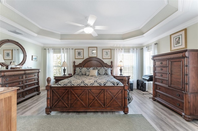 bedroom featuring a raised ceiling, ceiling fan, and multiple windows