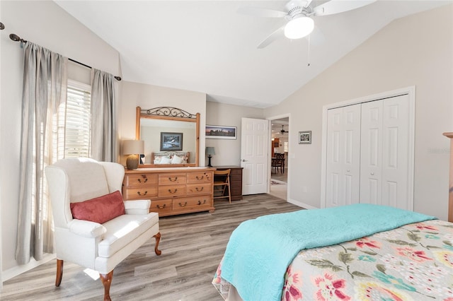 bedroom featuring ceiling fan, lofted ceiling, a closet, and light wood-type flooring