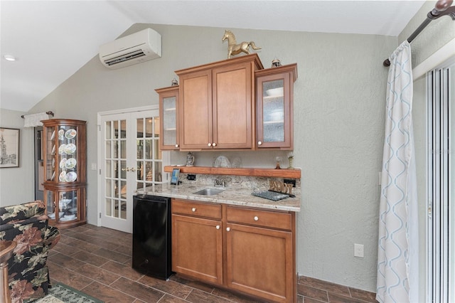 kitchen with french doors, sink, vaulted ceiling, black dishwasher, and a wall unit AC