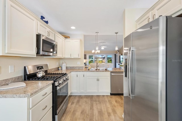 kitchen with sink, stainless steel appliances, decorative light fixtures, kitchen peninsula, and light wood-type flooring