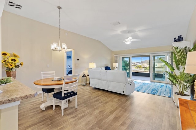 living room featuring washer / clothes dryer, ceiling fan with notable chandelier, vaulted ceiling, and light hardwood / wood-style floors