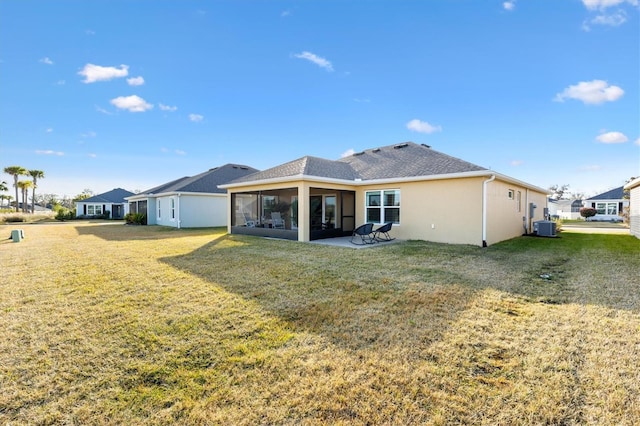 rear view of property with cooling unit, a sunroom, and a lawn