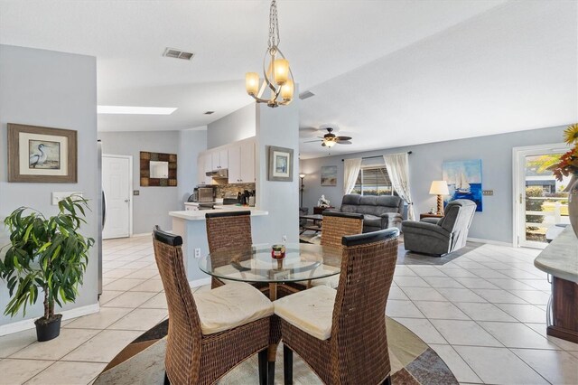 tiled dining space featuring lofted ceiling, ceiling fan with notable chandelier, and a healthy amount of sunlight