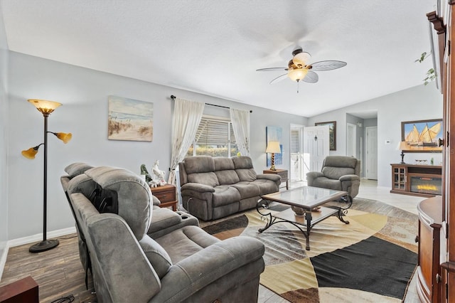 living room featuring lofted ceiling, a textured ceiling, light hardwood / wood-style floors, and ceiling fan