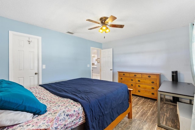 bedroom with a textured ceiling, dark hardwood / wood-style floors, and ceiling fan