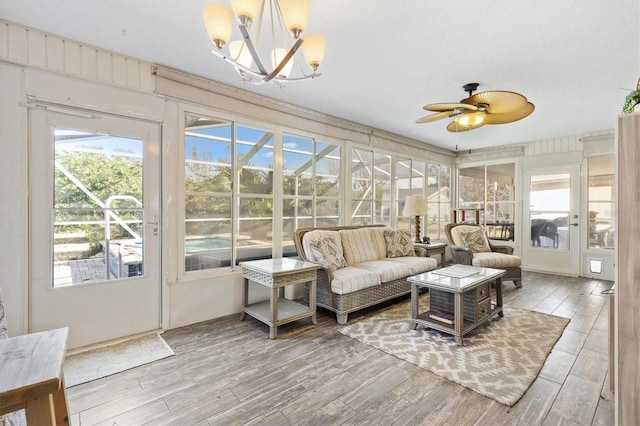 sunroom featuring ceiling fan with notable chandelier