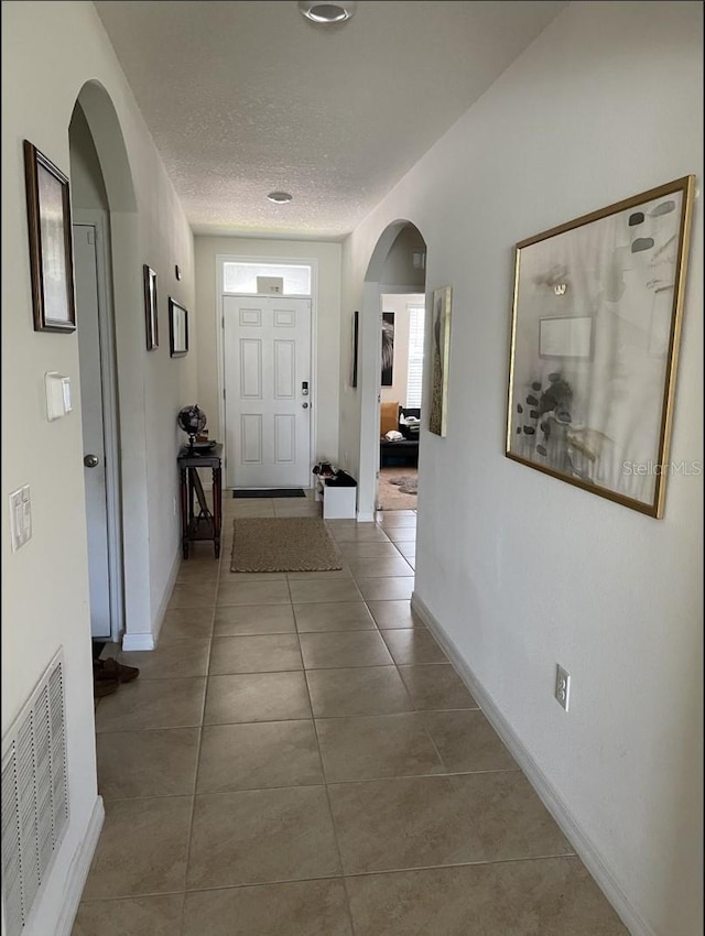 corridor with tile patterned floors and a textured ceiling