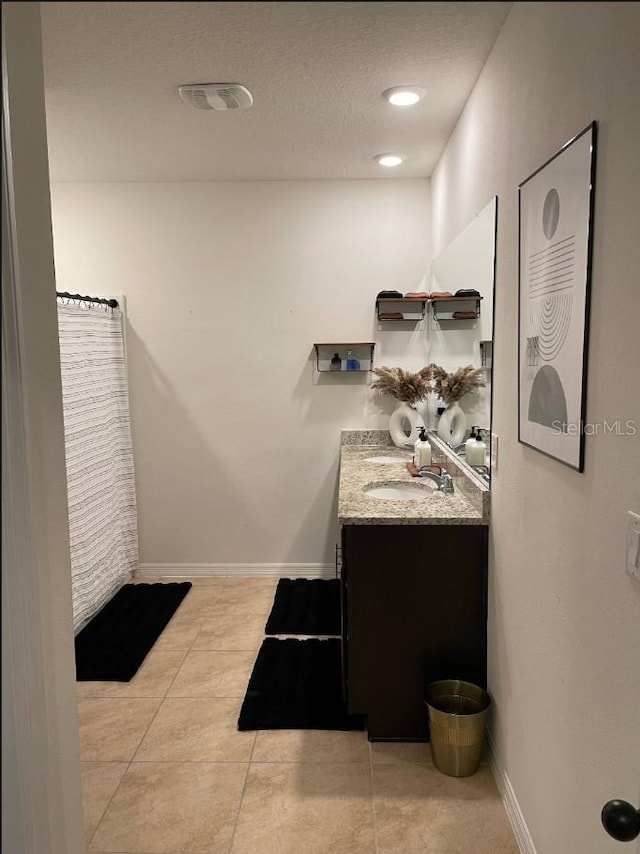 bathroom with tile patterned floors, vanity, and a textured ceiling